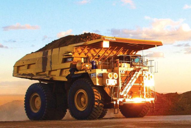 A Caterpillar branded digger full of rubble and soil