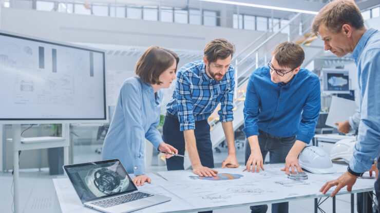 4 colleagues collaborate in a clinical looking open plan office