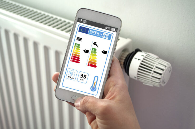 Energy units of a home displayed on a smartphone in front of a radiator