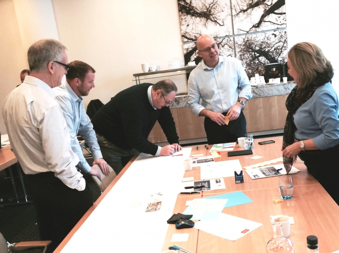 5 colleagues collaborate together across ASG branded papers on a table.