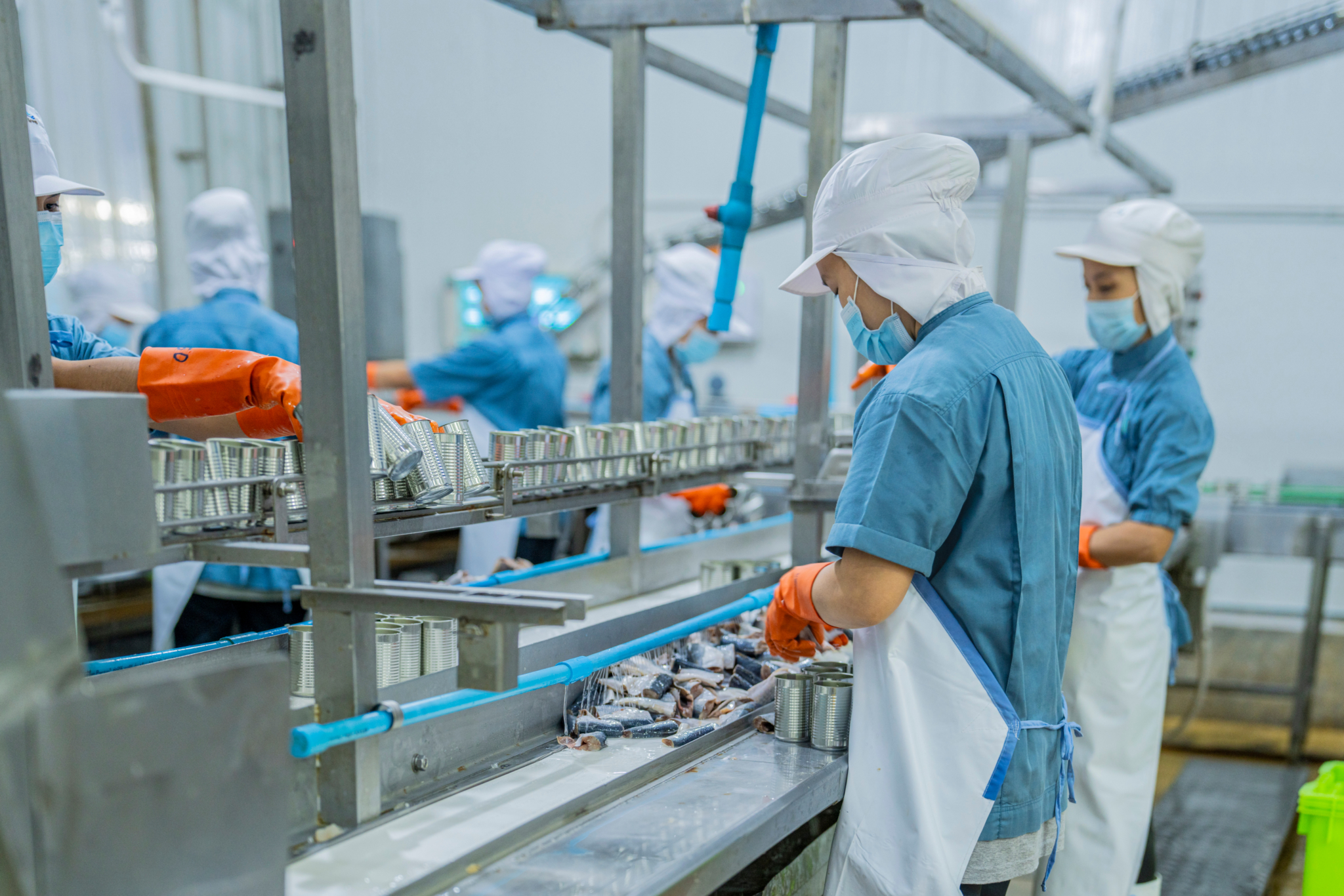 Masked and gloved workers work in a factory setting