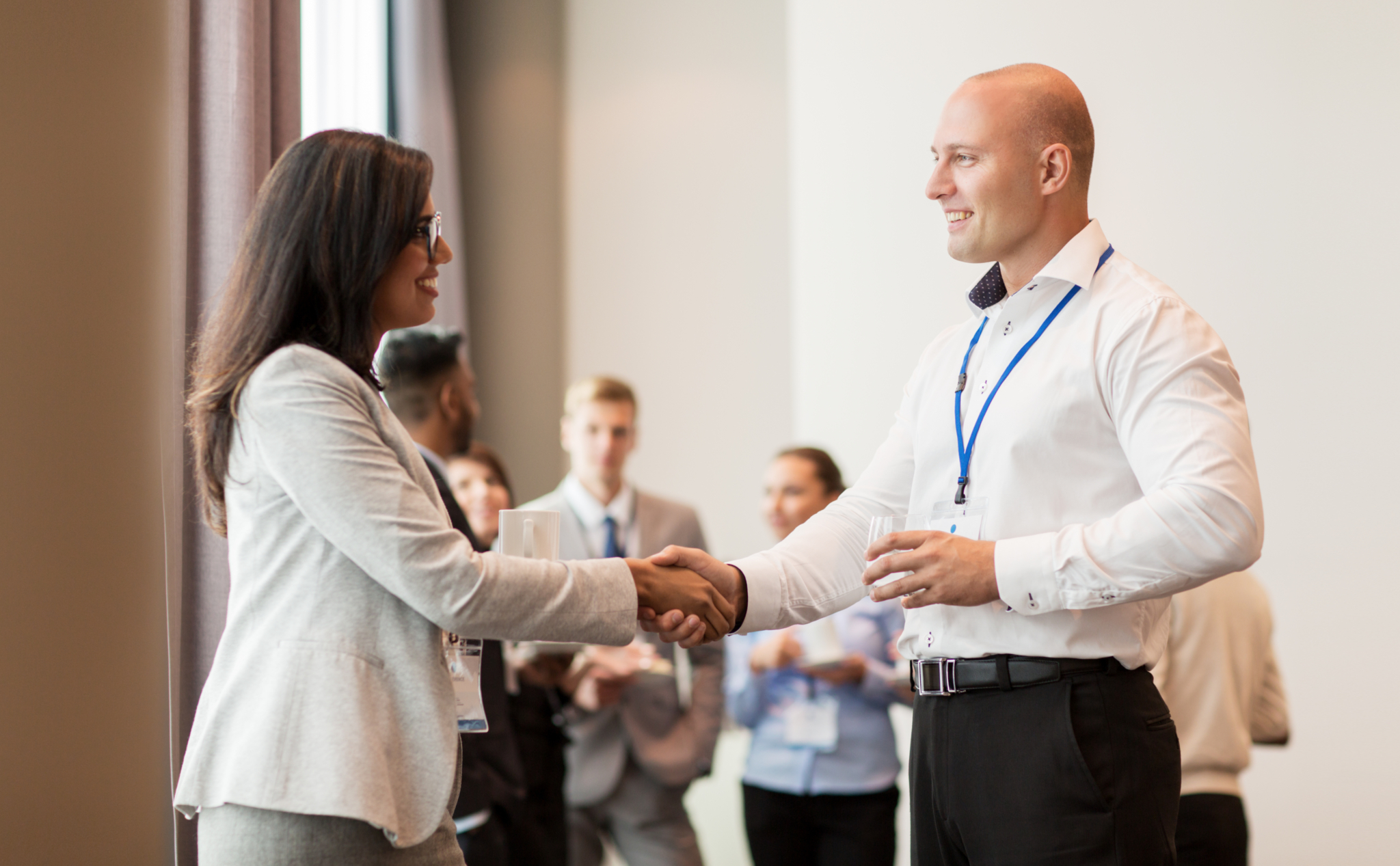 Two professionally dressed people greet and shake hands